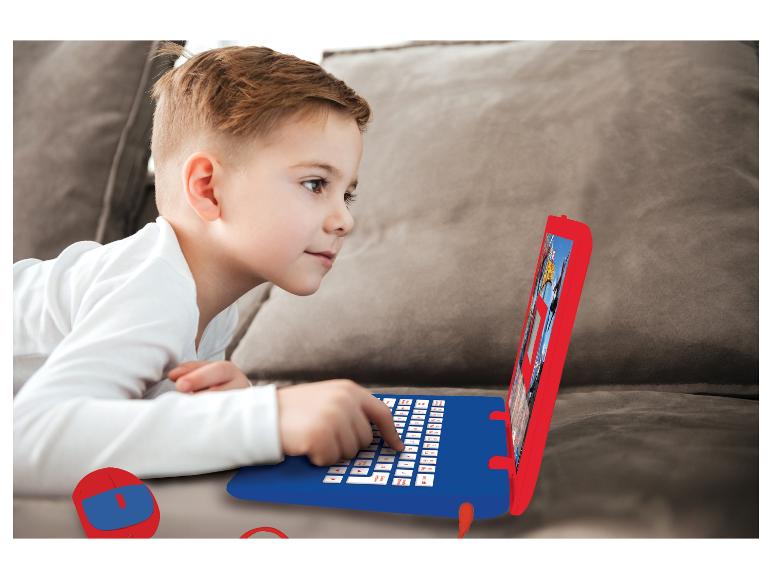 Un garçon joue sur un ordinateur portable jouet rouge et bleu sur un canapé.