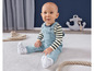 Un bébé dans une salopette bleue et un t-shirt rayé