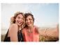 Deux femmes souriantes en maillots près de la mer.