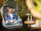 Une femme se détend dans un fauteuil suspendu dans le jardin.