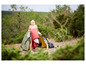 Une femme campe avec une tente, un sac de couchage et du matériel de cuisine dans la nature.