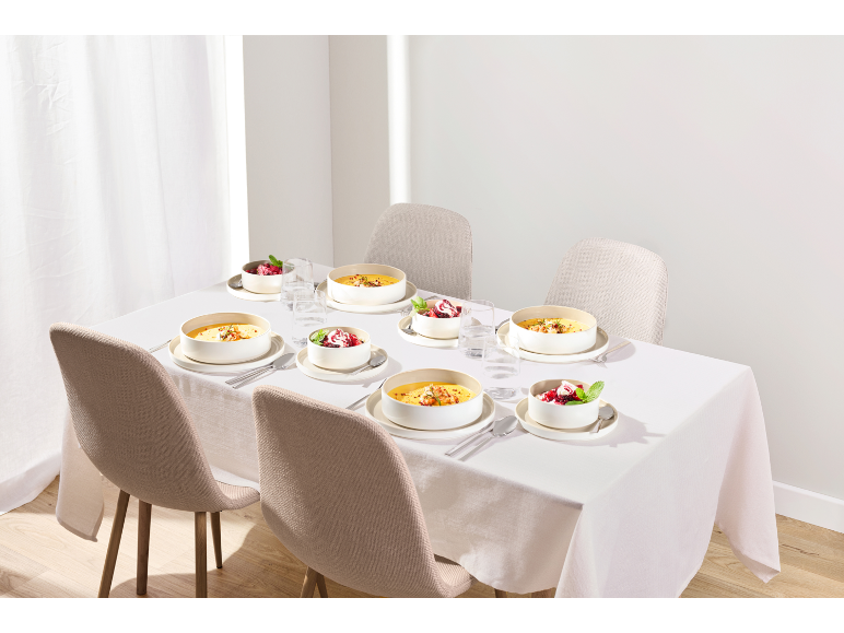 Table élégamment dressée avec des bols de soupe et de dessert sur une nappe blanche.