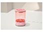 Appareil de beauté rose avec corps transparent, dessus à motifs et bouton d'alimentation.