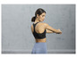 Une femme porte un soutien-gorge de sport noir et un legging bleu.