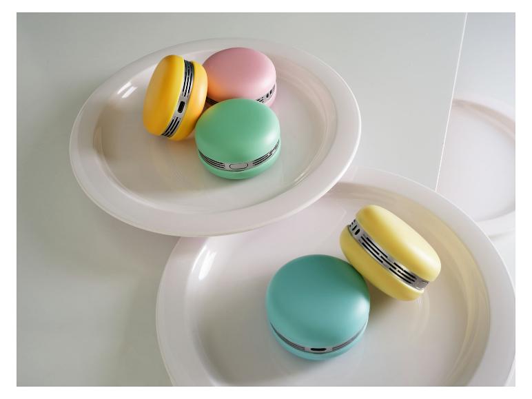 Mini ventilateurs colorés en forme de macaron sur des assiettes blanches.
