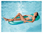 Une femme se détend sur une chaise longue gonflable dans une piscine.