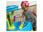 Un enfant joue avec une table d'eau avec une fontaine et des pelles.