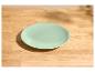 Assiette vert menthe sur une table en bois clair.
