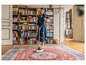 Une femme aspire un tapis avec un aspirateur.