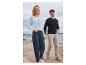 Une femme et un homme portant des pulls en tricot et des jeans sur la plage.