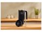 Mug thermique noir avec couvercle et paille, sur une table en bois dans une cuisine.