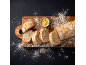 Pain ciabatta tranché sur une planche en bois avec du beurre et de la farine sur fond sombre.