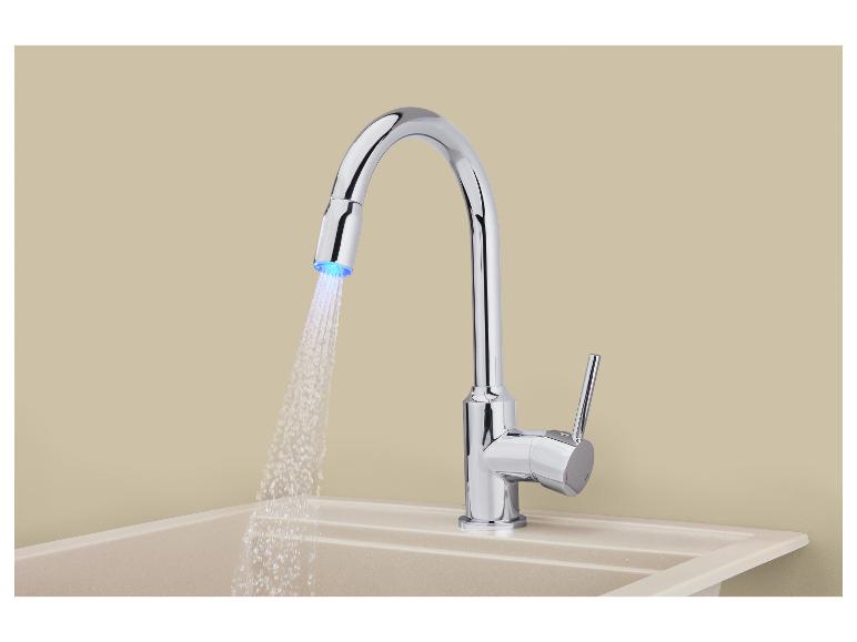 Robinet de cuisine chromé avec douchette extractible et lumière LED, au-dessus d'un évier beige.