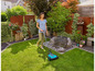 Une femme tond la pelouse avec une tondeuse à gazon Bosch dans un jardin.