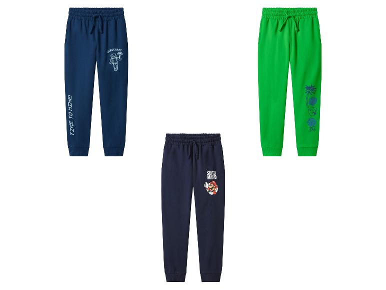 Trois pantalons de survêtement pour enfants : deux bleu foncé avec personnages de jeux, un vert thème tropical.