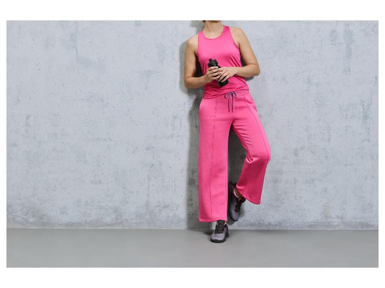 Une femme porte des vêtements de sport roses et des baskets noires