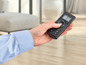 Une main tenant une télécommande noire avec un écran numérique.