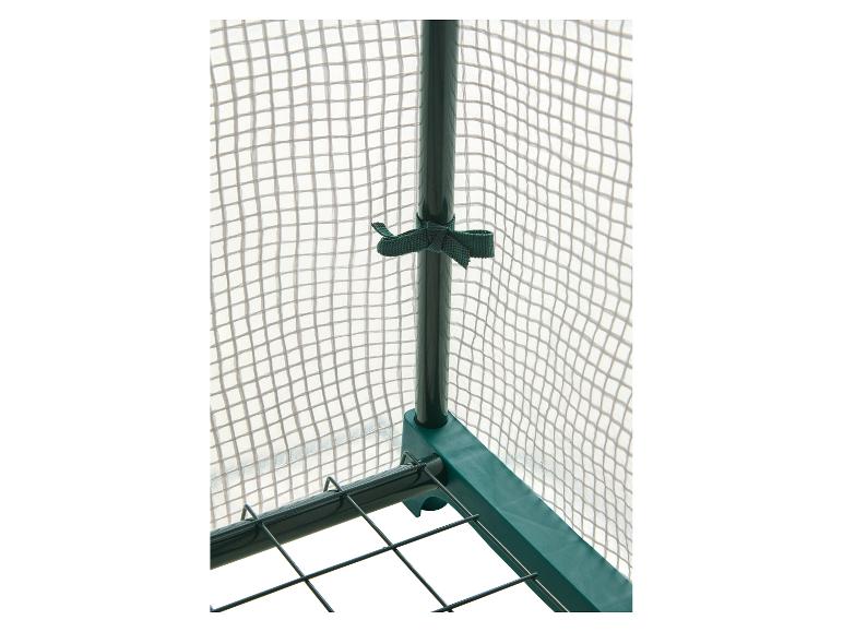 Détail de serre de jardin avec cadre vert et couverture en maille transparente.