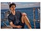 Un homme détendu en chemise et short foncés sur un yacht.