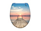 Abattant de WC avec une image d'une jetée sur l'eau au coucher du soleil.