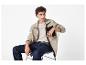 Homme assis sur une chaise, portant une veste polaire beige, un T-shirt clair et un jean.