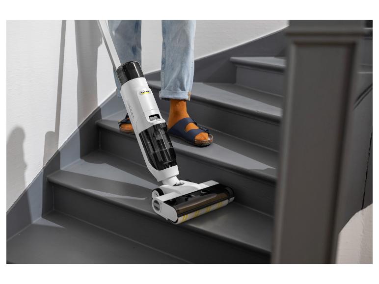Personne nettoyant des escaliers gris avec un nettoyeur de sol sans fil blanc.