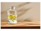 Distributeur de boissons en verre avec robinet, tranches de citron vert et glaçons sur une surface en bois.