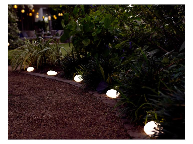 Lampes solaires en forme de galets éclairant un jardin.