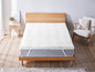 Un protège-matelas blanc sur un cadre de lit en bois.