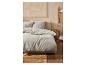Parure de lit grise et linge de maison dans une chambre à coucher stylée.