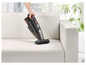 Un aspirateur à main Vax est utilisé pour nettoyer un canapé blanc.