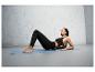 Une femme utilise une balle de massage sur un tapis de yoga.