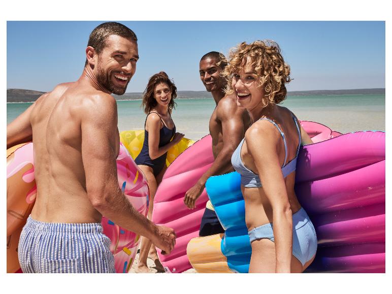 Des amis sur la plage avec des flotteurs en forme de donut et de glace.