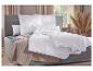 Lit avec cadre gris, literie blanche et couverture beige dans une chambre.