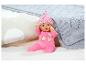 Poupée Baby Born avec une tenue rose et un bonnet sur un tapis en peluche blanc.