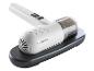 Aspirateur à main blanc avec bac à poussière transparent, en charge sur une base noire.