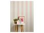 Papier peint rayé rose et blanc avec une plante, un cadre photo et des maisons décoratives sur une table.