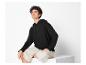 Une femme porte un sweat à capuche noir et un pantalon beige.