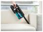 Une main tient un aspirateur sans fil pour nettoyer un canapé blanc.