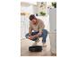 Un homme utilise un robot aspirateur dans une cuisine.