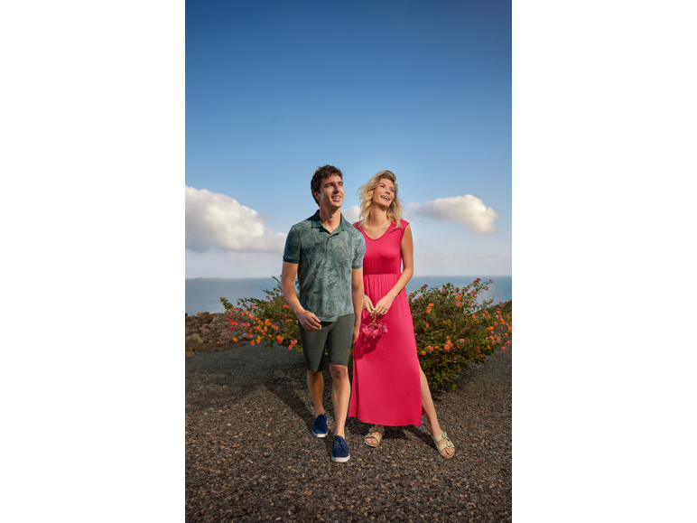 Homme en polo et short, femme en robe longue, tous deux souriants en extérieur.