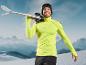 Un homme avec un pull jaune et des lunettes de ski porte des skis dans les montagnes.