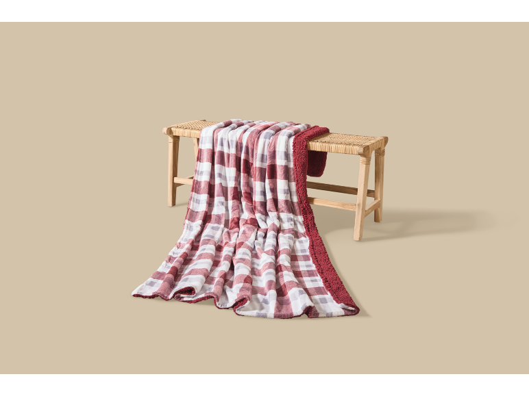Couverture à carreaux rouges et blancs négligemment posée sur un banc en bois.