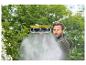 Homme nettoyant en extérieur avec une brosse qui pulvérise de l'eau.