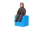 Enfant en combinaison léopard avec oreilles, assis sur un cube bleu.
