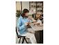 Une femme en chemise bleue lit un journal tout en buvant un café dans un café.