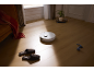 Aspirateur robot blanc sur un parquet dans un salon.