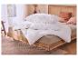 Couette et oreillers blancs sur un lit en bois avec literie beige dans une chambre.