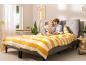 Couple détendu sur un lit gris avec couette jaune rayée.