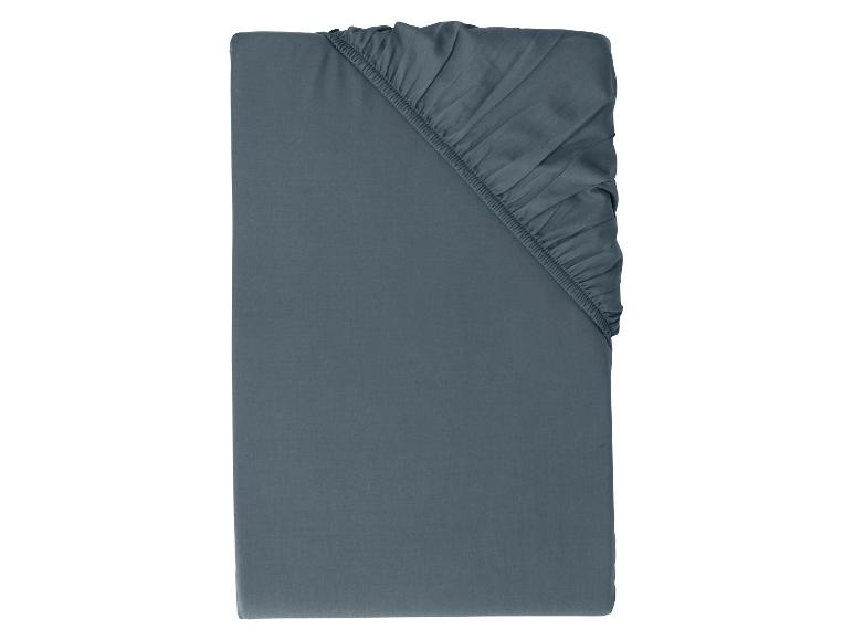 Drap-housse bleu foncé avec coins élastiqués, plié soigneusement sur fond blanc.